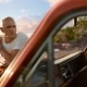 Kelly Slater ob obali med sončnim zahodom, naslonjen na retro terensko vozilo, nosi uro Breitling Superocean Heritage B31 Automatic 40 Kelly Slater Limited Edition. / Kelly Slater leaning on a retro truck at sunset, wearing the Breitling Superocean Heritage B31 Automatic 40 Kelly Slater Limited Edition watch.