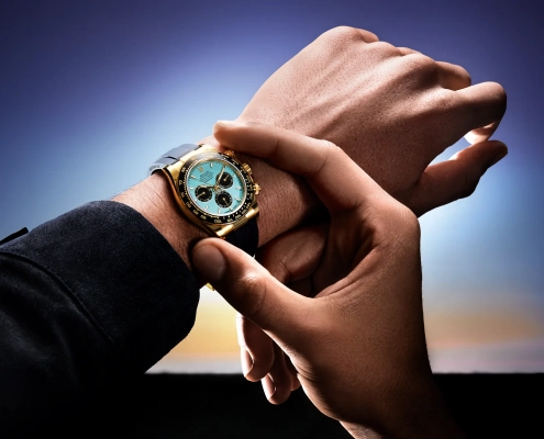 Ura Rolex Oyster Perpetual Cosmograph Daytona z ledeno modro številčnico, kronografskimi števci in 18-karatnim zlatim ohišjem, na črnem Oysterflex paščku – fotografirano v zlati svetlobi sončnega zahoda. (David Magazine for Men with Style) / Rolex Oyster Perpetual Cosmograph Daytona with an ice blue dial, chronograph counters, and 18k gold case on a black Oysterflex strap – photographed in golden sunset light. (David Magazine for Men with Style)