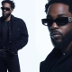 Kendrick Lamar nosi črna sončna očala CHANEL iz kolekcije pomlad–poletje 2025, oblečen v črn plašč z retro minimalističnim stilom, fotografirano v studiu Karima Sadlija. / Kendrick Lamar wears black CHANEL sunglasses from the Spring–Summer 2025 eyewear collection, styled in a black retro coat, photographed by Karim Sadli.