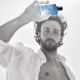 Aaron Taylor-Johnson drži stekleničko parfuma Giorgio Armani Acqua Di Giò Profondo Eau de Toilette v svetli, poletni atmosferi – simbol svežine, moškosti in povezave z naravo. / Aaron Taylor-Johnson holding a bottle of Giorgio Armani Acqua Di Giò Profondo Eau de Toilette in a bright summer setting – a symbol of freshness, masculinity, and connection with nature.