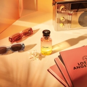 Parfumska voda Louis Vuitton Sun Song s sončno rumeno stekleničko, sončnimi očali in vodičem Los Angeles ob zlatem soncu. (David Magazine for Men with Style) / Louis Vuitton Sun Song perfume in a sunny yellow bottle, styled with sunglasses and a Los Angeles city guide under golden light. (David Magazine for Men with Style)