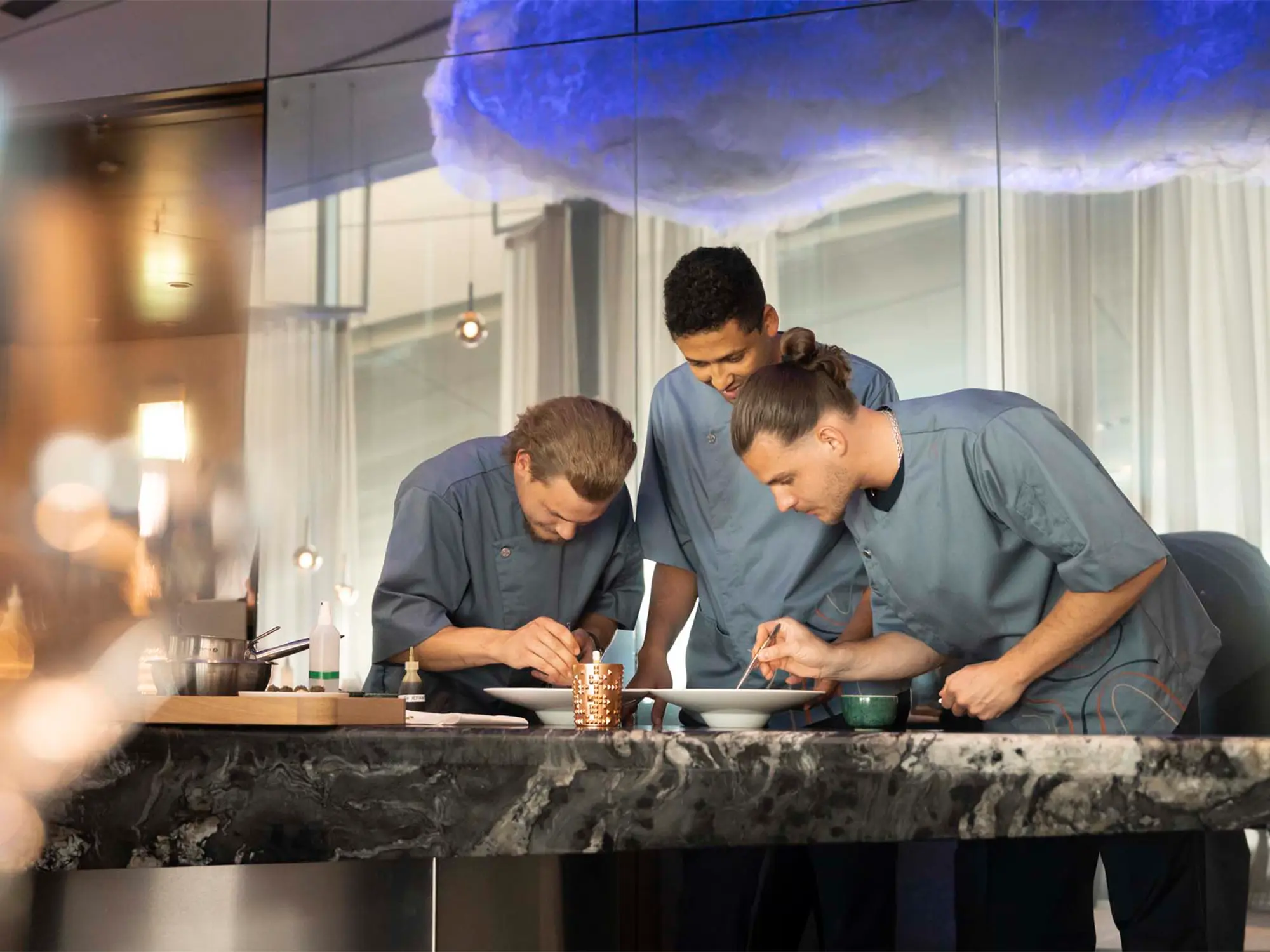 Kuharska ekipa The Cloud by Käfer s kuharskim mojstrom Jensom Madsenom med pripravo jedi v vrhunski restavraciji BMW Welt v Münchnu. (David Magazine for Men with Style) / The culinary team of The Cloud by Käfer, led by head chef Jens Madsen, preparing dishes in the fine dining restaurant at BMW Welt, Munich. (David Magazine for Men with Style)