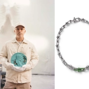 Sodobni umetnik Daniel Arsham v studiu drži bronasto skulpturo penija poleg ekskluzivne Tiffany & Co. HardWear ogrlice iz belega zlata, posute z diamanti in tsavoriti. / Contemporary artist Daniel Arsham holding a bronze penny sculpture beside the limited-edition Tiffany & Co. HardWear necklace adorned with diamonds and tsavorites.