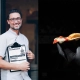 Greg Yurkovich, soustanovitelj POPS Aperitivo Ljubljana, s podpisano jedilno karto in gurmanskim koščkom pice – pogovor za revijo David – revija za moške s stilom. / Greg Yurkovich, co-founder of POPS Aperitivo Ljubljana, holding the signature menu and showcasing a slice of gourmet pizza – featured in David, men's magazine with style.