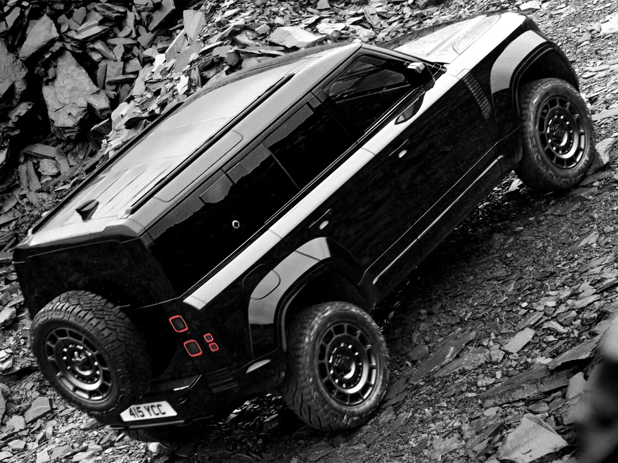 Land Rover Defender OCTA Black Edition med ekstremno terensko vožnjo po kamnitem terenu – luksuzni SUV s karakterjem, predstavljen v reviji David za moške s stilom.