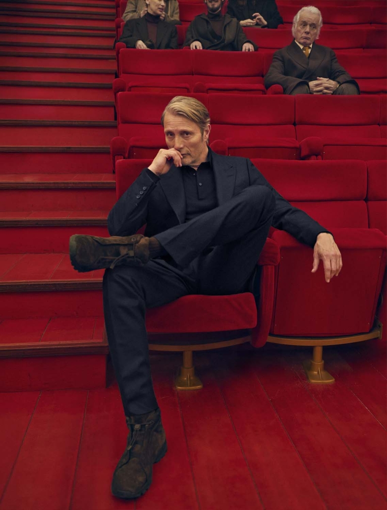 Igralec Mads Mikkelsen oblečen v elegantno pepita vzorčasto ZEGNA obleko, sedi v klasični italijanski kavarni in pije kavo – sofisticirana interpretacija torinskega stila za jesen/zimo 2025.
Actor Mads Mikkelsen wearing an elegant houndstooth ZEGNA suit, seated in a classic Italian café sipping coffee – a sophisticated take on the Turin style for Fall/Winter 2025.