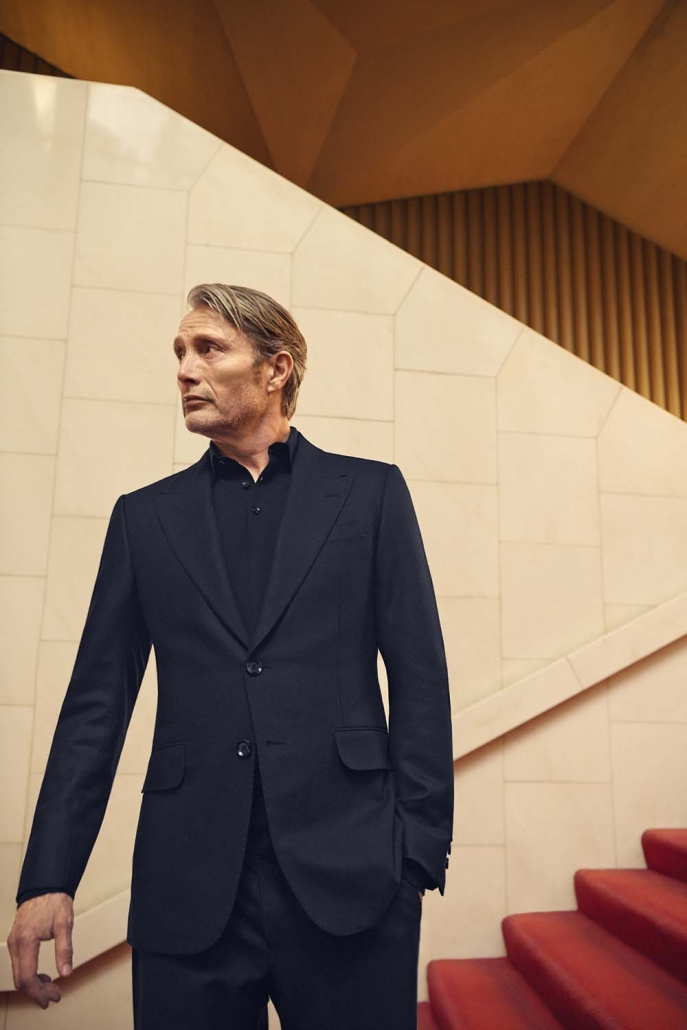 Igralec Mads Mikkelsen oblečen v elegantno pepita vzorčasto ZEGNA obleko, sedi v klasični italijanski kavarni in pije kavo – sofisticirana interpretacija torinskega stila za jesen/zimo 2025.
Actor Mads Mikkelsen wearing an elegant houndstooth ZEGNA suit, seated in a classic Italian café sipping coffee – a sophisticated take on the Turin style for Fall/Winter 2025.
