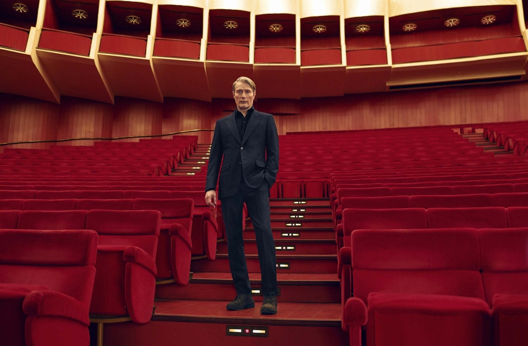 Igralec Mads Mikkelsen oblečen v elegantno pepita vzorčasto ZEGNA obleko, sedi v klasični italijanski kavarni in pije kavo – sofisticirana interpretacija torinskega stila za jesen/zimo 2025.
Actor Mads Mikkelsen wearing an elegant houndstooth ZEGNA suit, seated in a classic Italian café sipping coffee – a sophisticated take on the Turin style for Fall/Winter 2025.