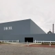 Zunanjost prizorišča modne revije Christian Dior jesen/zima 2025–2026 v Parizu, z moderno geometrično stavbo in razgledom na Eifflov stolp. Exterior of the Christian Dior Fall/Winter 2025–2026 fashion show venue in Paris, featuring a modern geometric structure and view of the Eiffel Tower.