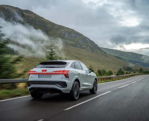 Novi Audi Q3 2025 vozi po mokri gorski cesti, obdani z meglo in zelenjem.