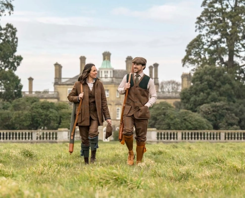 Moški in ženska v elegantnih tvid oblačilih Holland & Holland, med sprehodom po angleškem podeželju.
