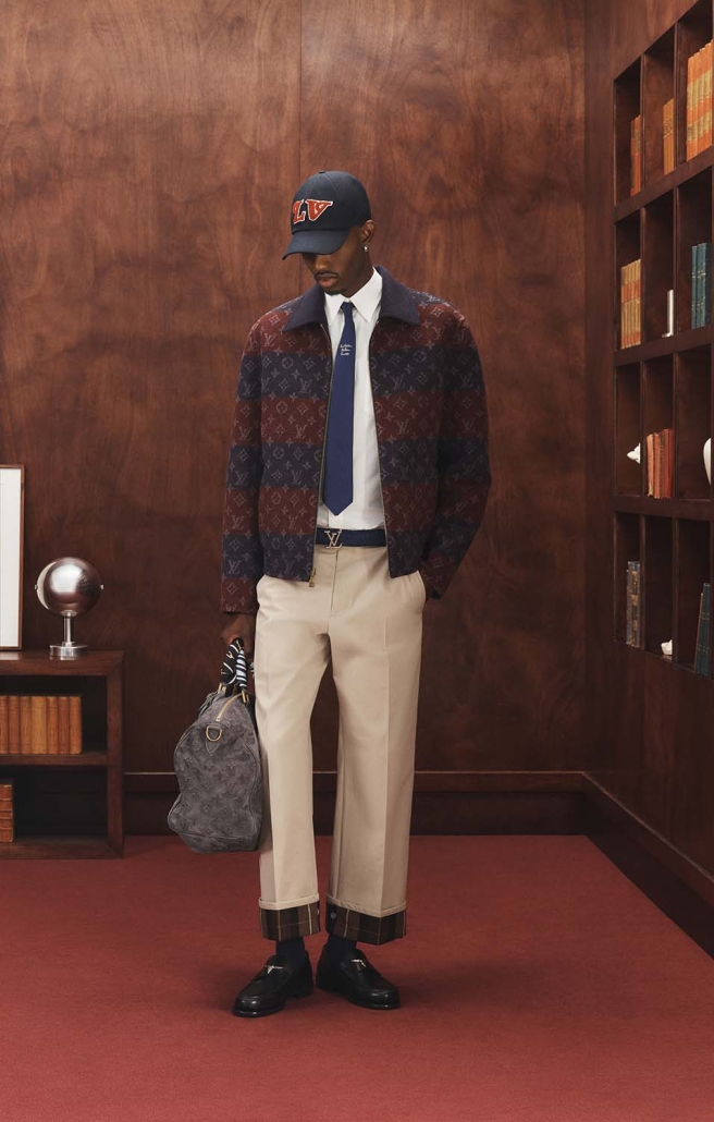 Moški model v preppy kombinaciji Louis Vuitton Ivy League kapsule 2025 s torbo in monogram jakno.