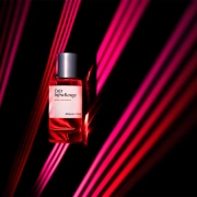 Steklenička parfuma Cuir InfraRouge Maison Crivelli z rožnatimi laserskimi žarki v ozadju