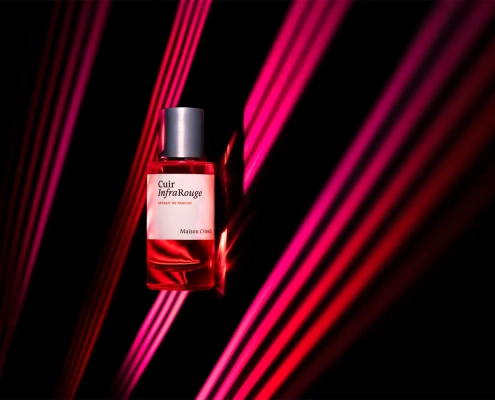 Steklenička parfuma Cuir InfraRouge Maison Crivelli z rožnatimi laserskimi žarki v ozadju