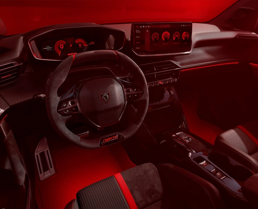 Notranjost novega Peugeot E-208 GTi s športnim volanom, digitalnimi merilniki in rdečo ambientalno osvetlitvijo.