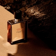 Terre d’Hermès Eau de Parfum Intense steklenička na pesku ob kamnu.