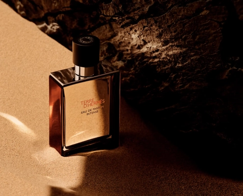 Terre d’Hermès Eau de Parfum Intense steklenička na pesku ob kamnu.