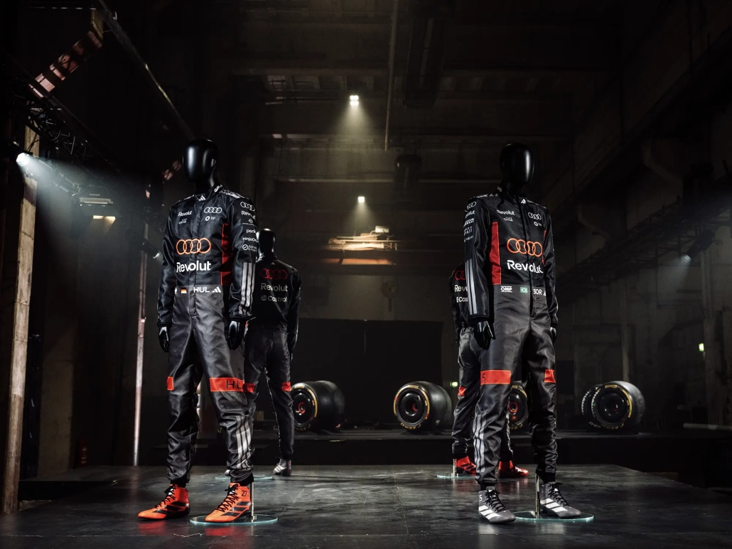 KO DIRKANJE NAVDIHNE MODO: GLOBALNA KOLEKCIJA ADIDAS X AUDI Ko se svet Formule 1 sreča z uličnim stilom, rezultat ni zgolj navijaška kolekcija, temveč modna izjava. Nova kolekcija adidas x Audi Revolut F1 Team je prav to – premišljeno oblikovan spoj vrhunskega motošporta, sodobne estetike in funkcionalne mode, ki briše meje med dirkališčem in mestnim asfaltom. To ni le oblačilo za navijače, temveč garderoba za tiste, ki Formulo 1 ne spremljajo samo ob nedeljah, ampak jo živijo kot del identitete. Sodelovanje med znamkama adidas in Audi v okviru projekta Audi Revolut F1 Team prinaša kolekcijo, ki deluje samozavestno, tehnično in presenetljivo elegantno. Že na prvi pogled je jasno, da ne gre za klasično »merch« linijo s kričečimi logotipi, temveč za sodobno športno modo, ki se brez težav znajde tako v paddocku kot na mestnih ulicah Milana, Berlina ali Ljubljane. Barvna paleta kolekcije je umirjena, a izrazito prepoznavna. V ospredju so sofisticirani sivo-krem odtenki, ki črpajo navdih iz titanium barve Audijevega dirkalnika, dopolnjujejo pa jih natančno odmerjeni rdeči poudarki. Ta kontrast ustvarja vizualno napetost – dovolj subtilno za vsakodnevno nošenje, a dovolj drzno, da jasno sporoča pripadnost svetu najvišjega razreda motošporta. Kolekcija ne kriči po pozornosti, temveč jo pridobi z detajli.