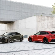 Audi RS 5 v sivi in rdeči barvi, parkiran pred moderno arhitekturo.