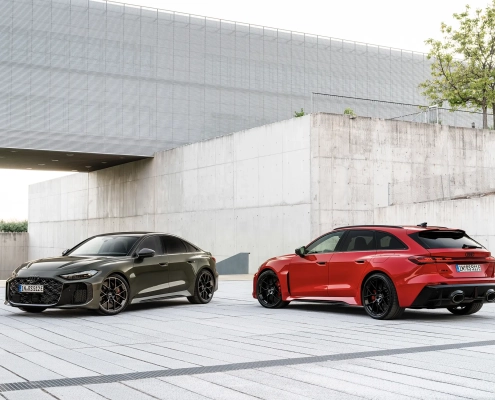 Audi RS 5 v sivi in rdeči barvi, parkiran pred moderno arhitekturo.