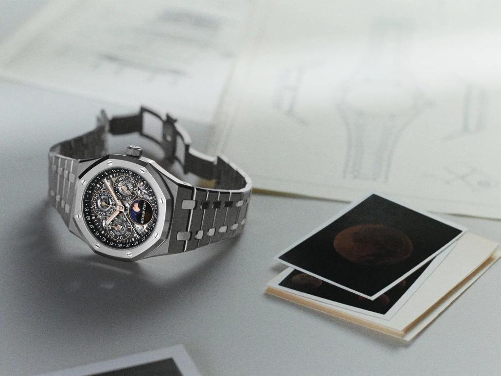 Audemars Piguet Royal Oak z odprtim večnim koledarjem in safirno številčnico na elegantni podlagi tehničnih skic.