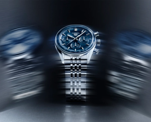 TAG Heuer Carrera kronograf z modro številčnico in jekleno zapestnico v dinamični svetlobni kompoziciji.