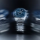 TAG Heuer Carrera kronograf z modro številčnico in jekleno zapestnico v dinamični svetlobni kompoziciji.