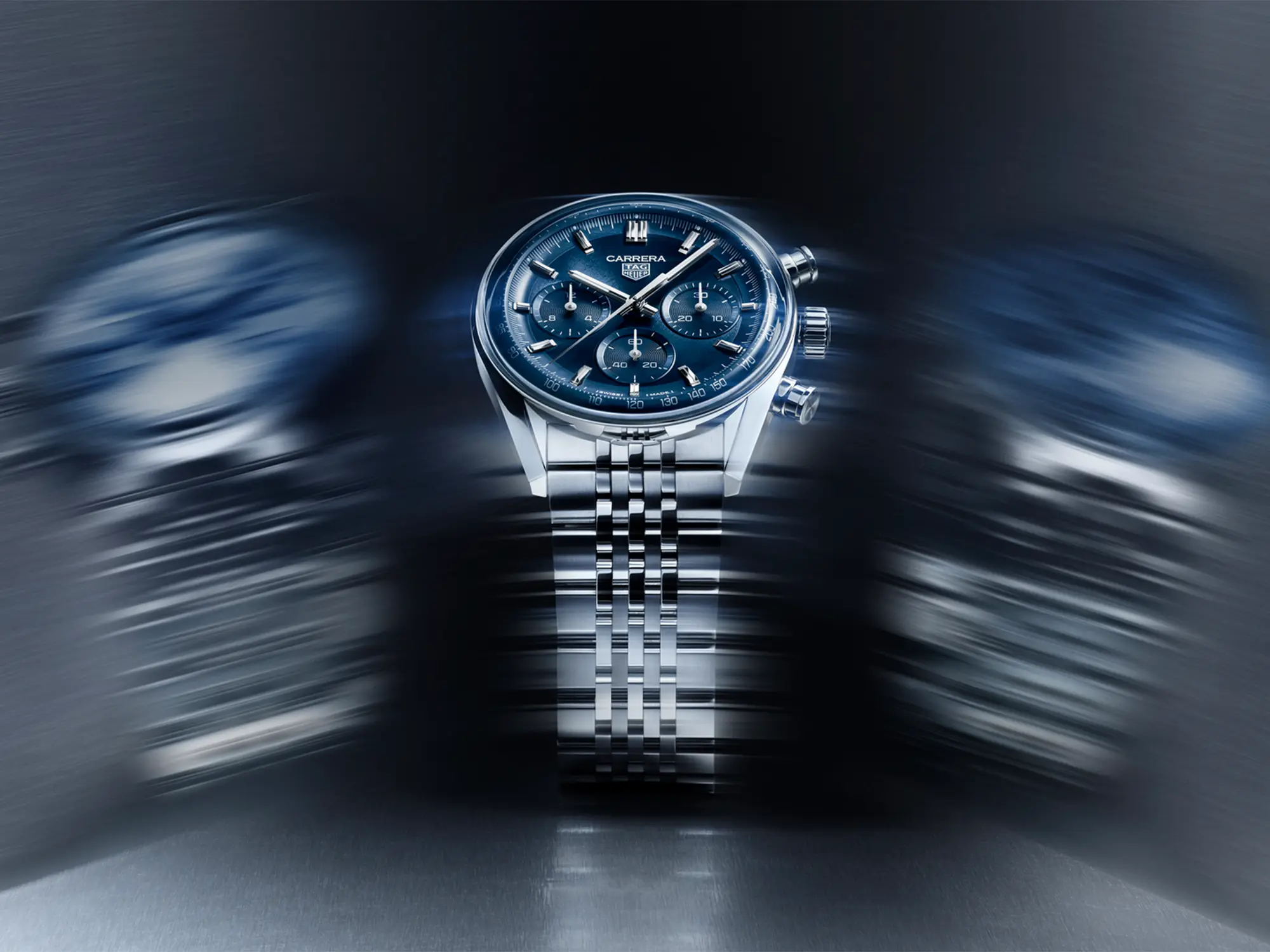 TAG Heuer Carrera kronograf z modro številčnico in jekleno zapestnico v dinamični svetlobni kompoziciji.