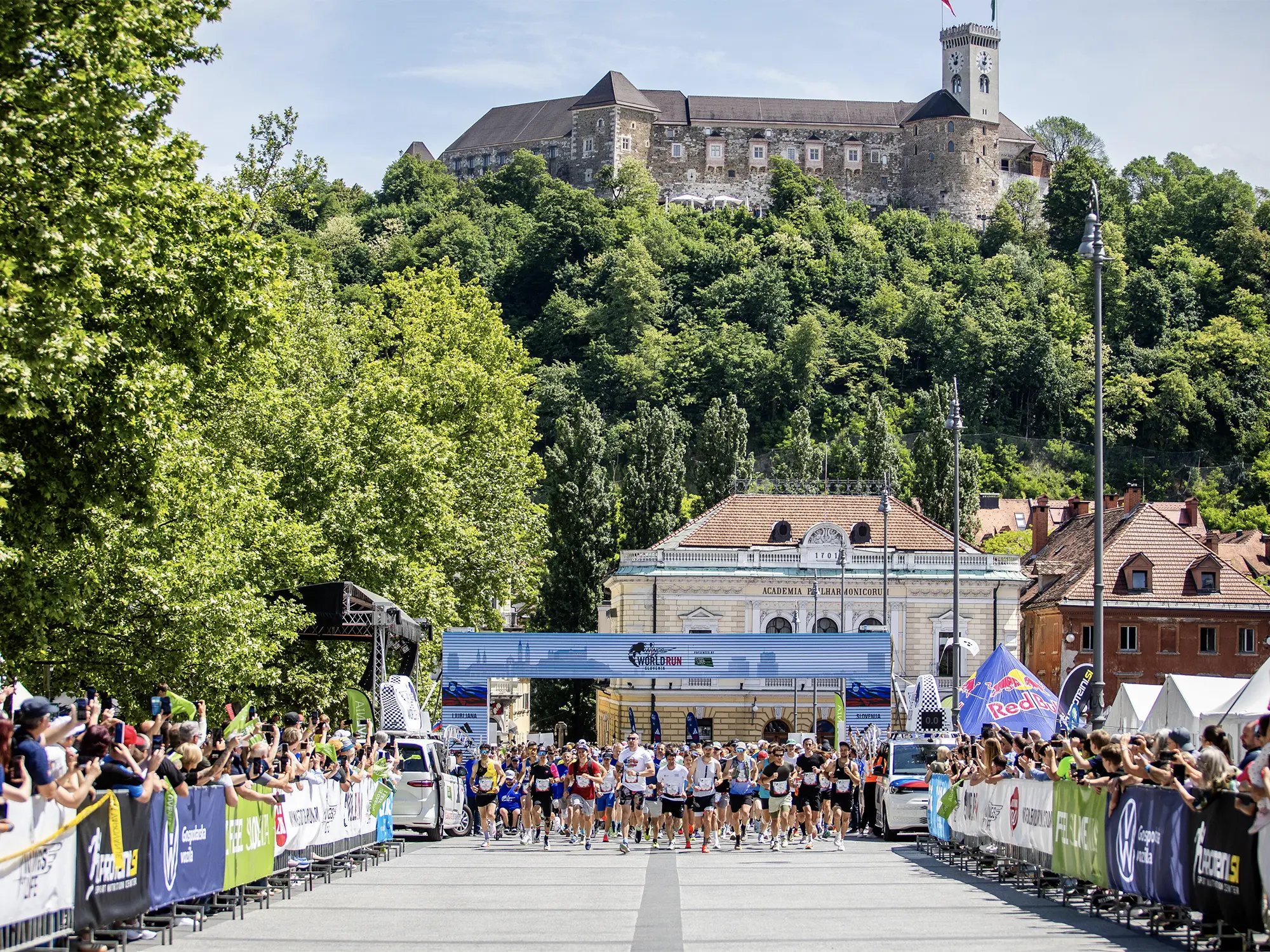 Tekači na startu Wings for Life World Run na Kongresnem trgu v Ljubljani z Ljubljanskim gradom v ozadju.