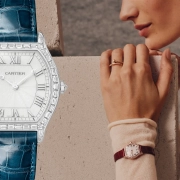 Ura Cartier Tortue z diamantnim ohišjem in modrim paščkom ob portretu ženske z uro na zapestju